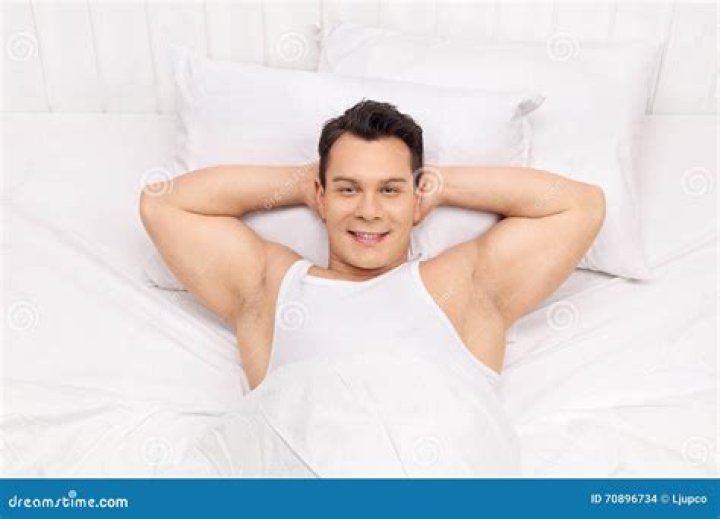 a man laying in bed with tattoos on his chest and chest is smiling at