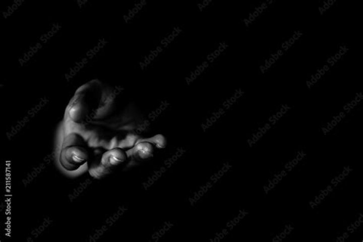 hand in darkness holding a globe that is lit up