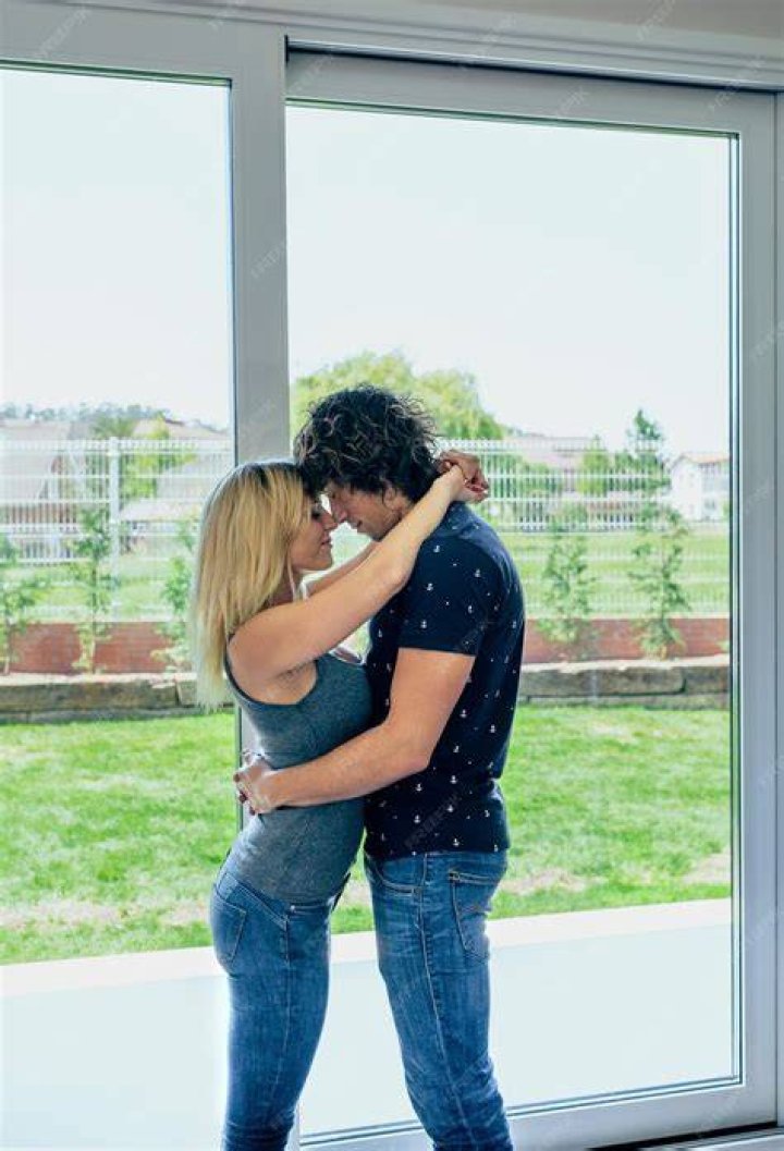 Kissing couple at home standing in door frame in living room Kissing couple at home standing in door frame in living room