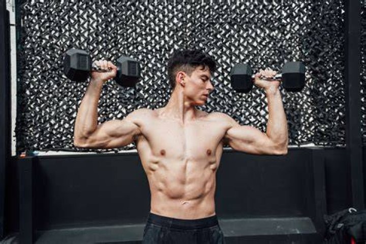 man lifting dumbbells to build arm muscles in gymconcept of exercise and health care