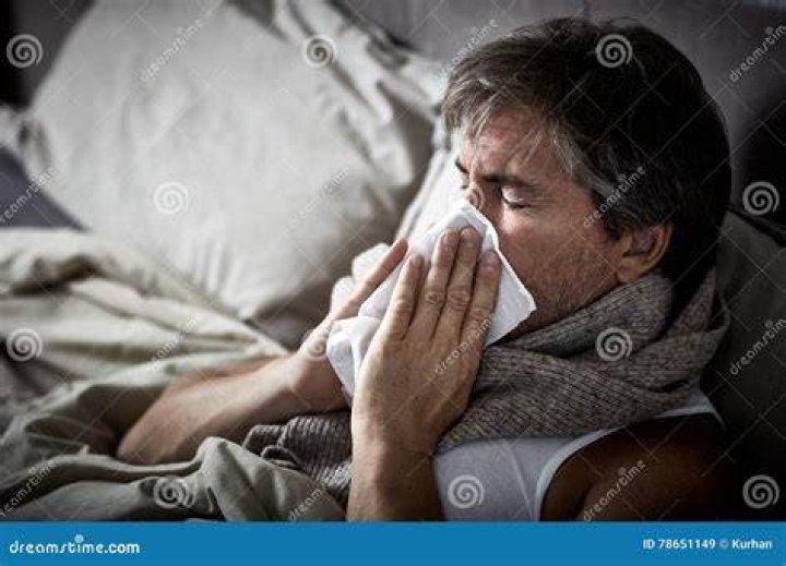 Man with a cold lying in sofa holding tissues man with a cold lying in sofa holding tissues