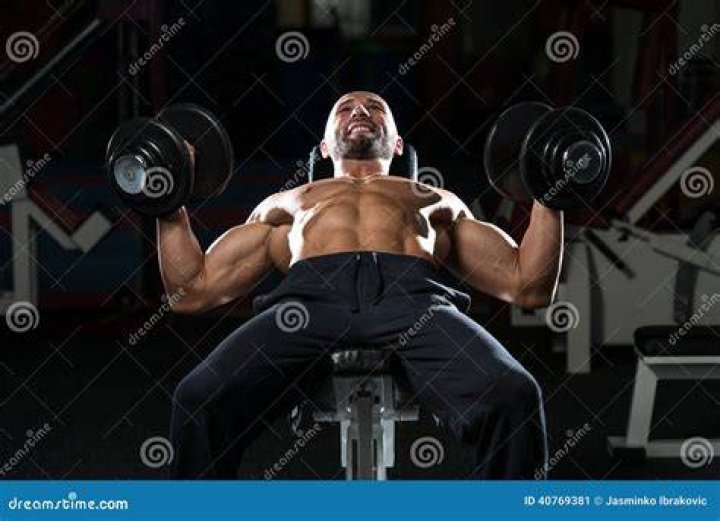 mature man doing dumbbell incline bench press workout