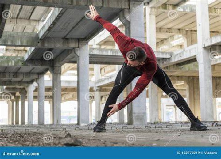 muscular man warming up on treadmill in a health club