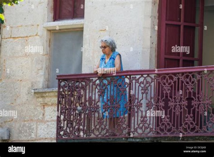 Old woman looking over balcony in greece
