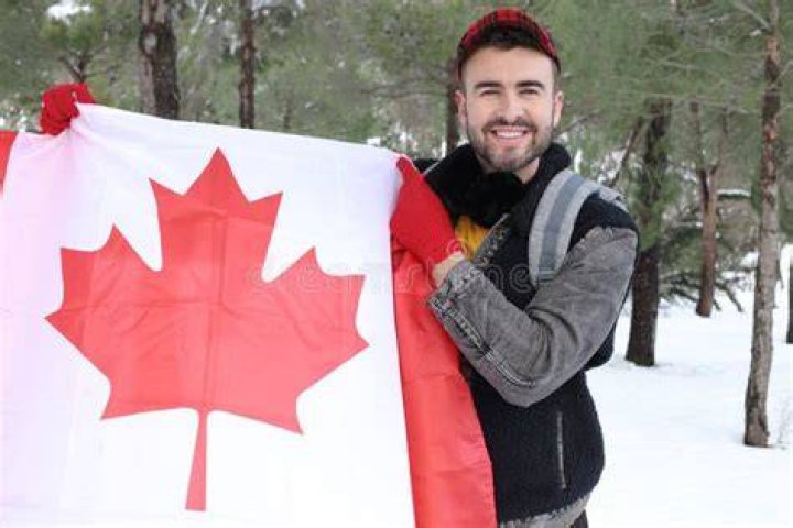 person holding Canadian flag with mountains and a lake in the background