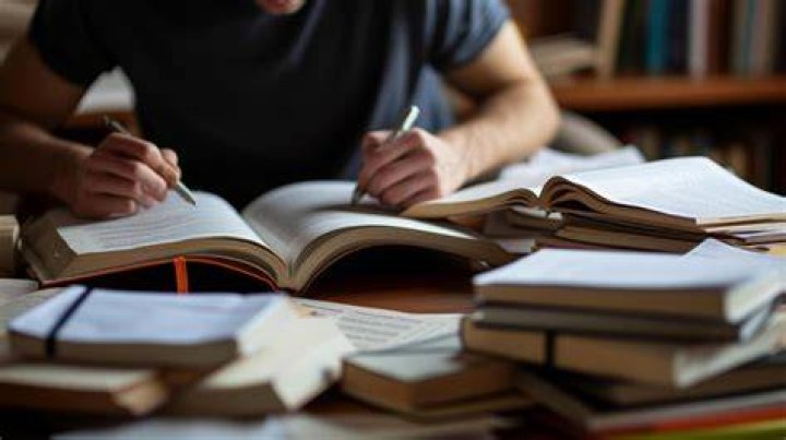 person studying around piles of books