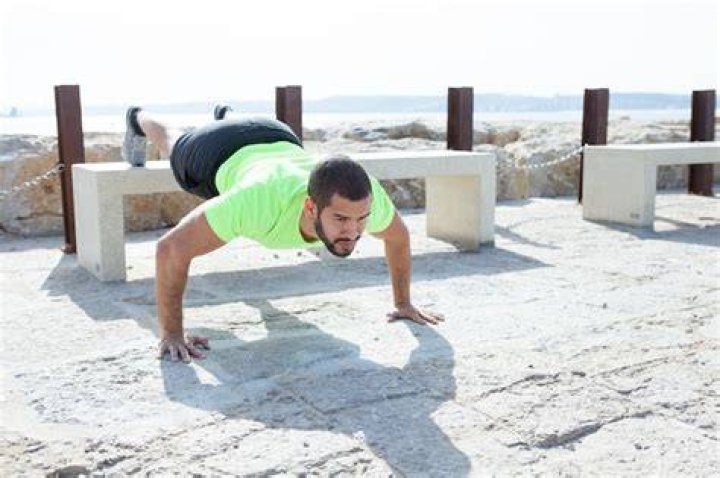strong man doing feet elevated push ups at seaside