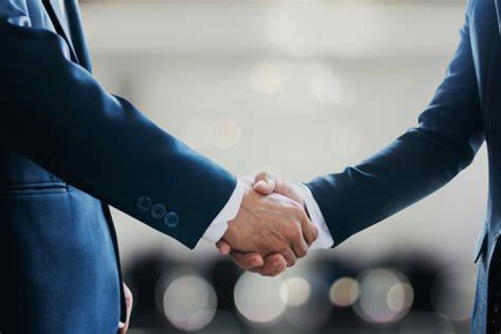 two people shaking hands over a table