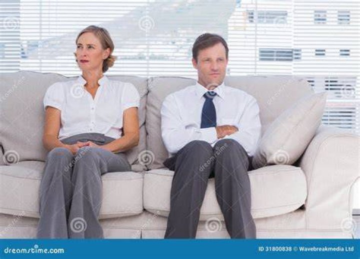 two people sitting on couch talking
