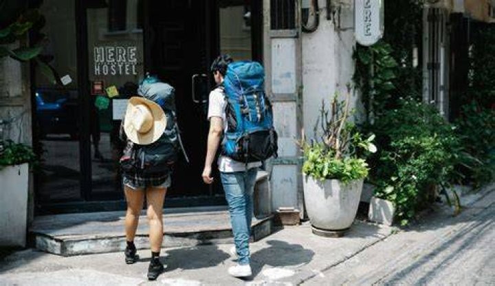 two travelers with backpacks entering a hostel