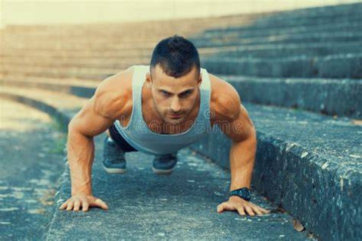 young man doing push ups while exercising at park